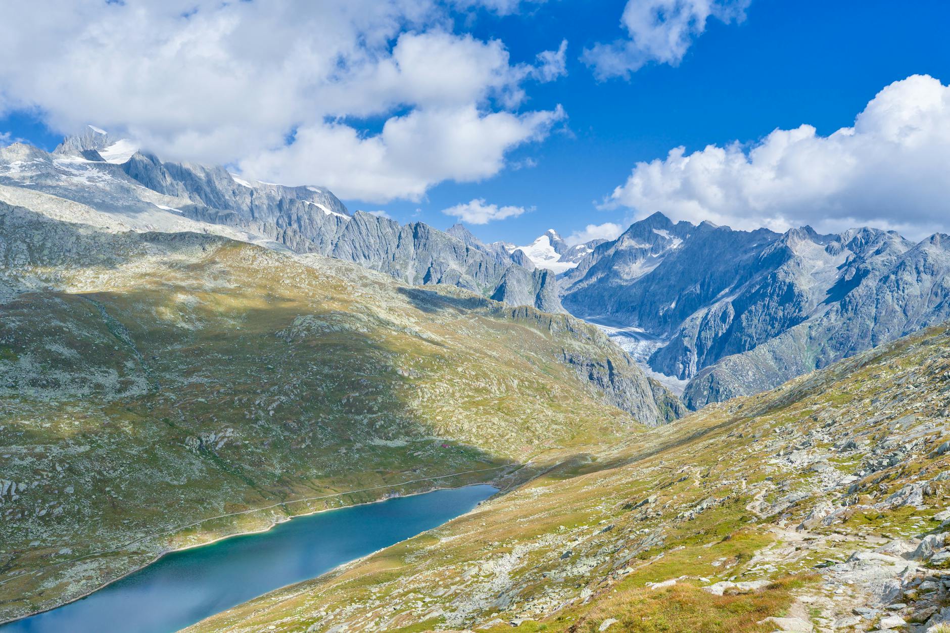 Jezioro w szwajcarskich Alpach otoczone skalistymi, ośnieżonymi szczytami
