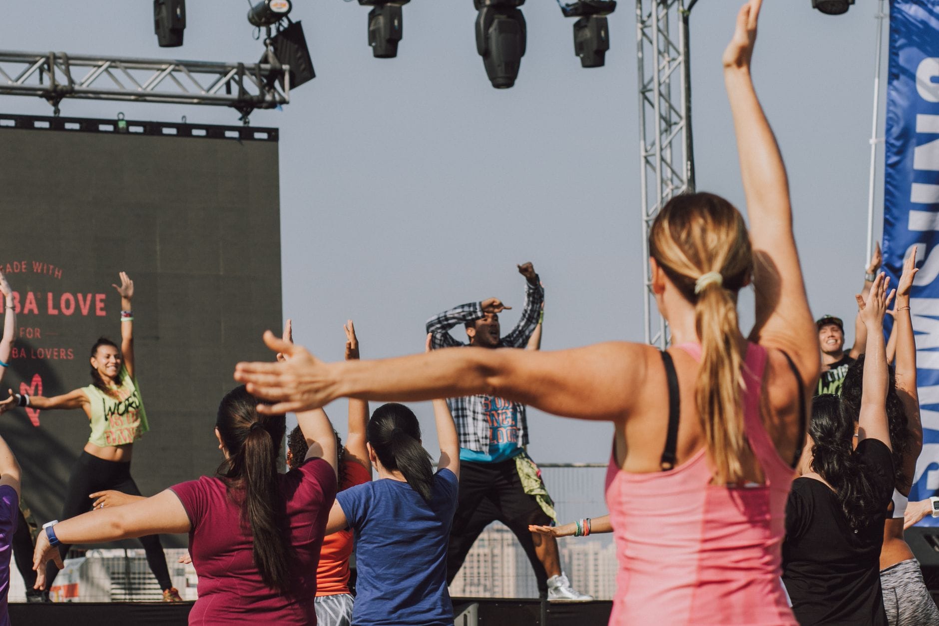 Zumba online dla początkujących: prosty plan treningu tanecznego w domu kroku po kroku Grupa osób ćwiczących zumbę na świeżym powietrzu z instruktorem