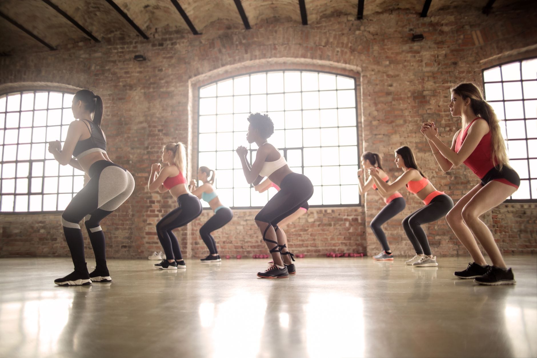 Kobiety na zajęciach fitness wykonujące przysiady w industrialnej sali