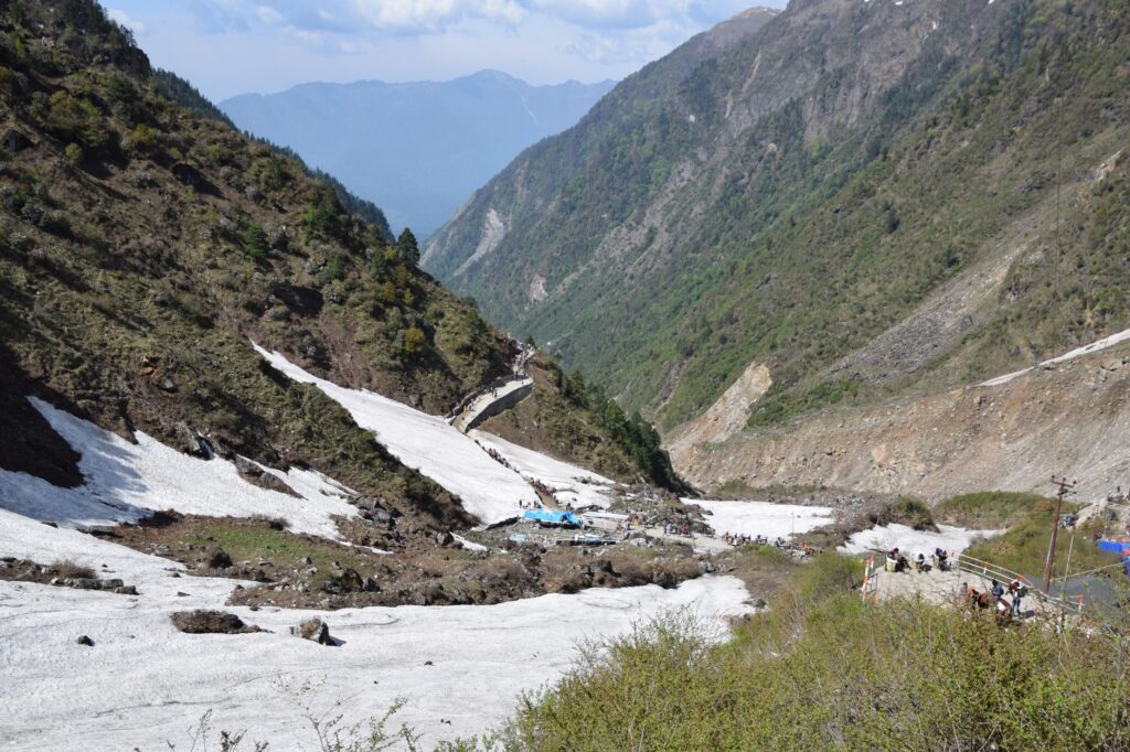 Turyści wędrujący przez dolinę Kedarnath wśród ośnieżonych gór